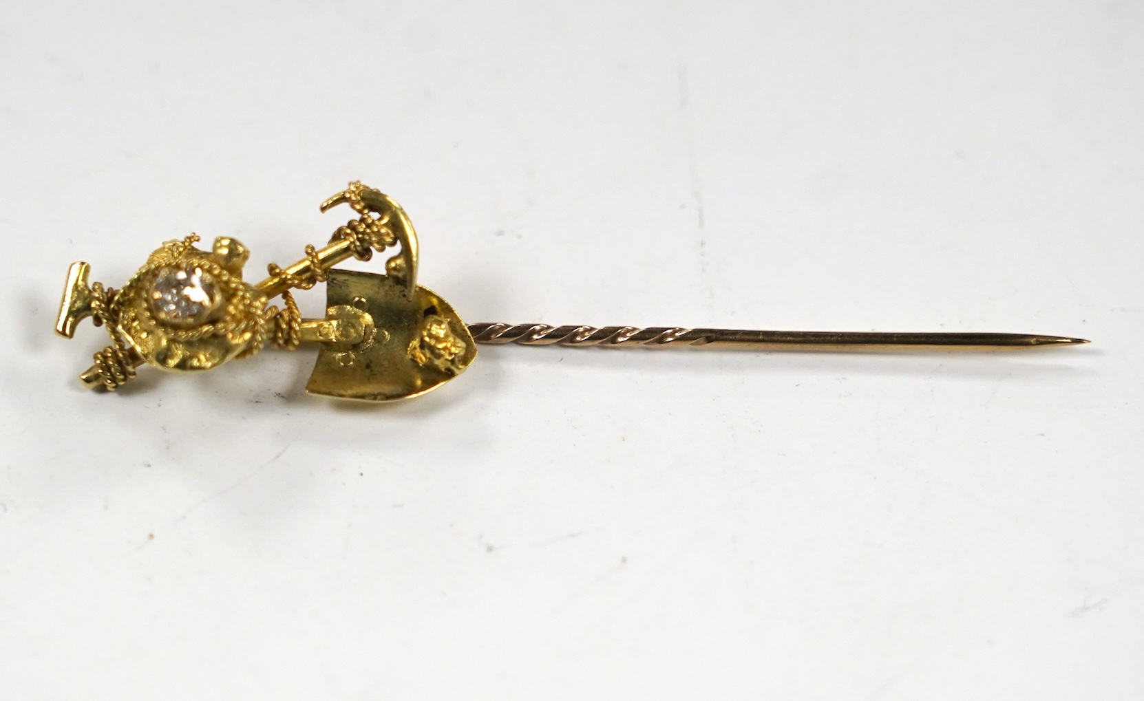 An early 20th century 9ct and diamond set 'Australian miner's' stick pin, 63mm, 4 grams.